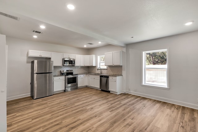 kitchen with white cabinets, sink, plenty of natural light, light hardwood / wood-style floors, and stainless steel appliances