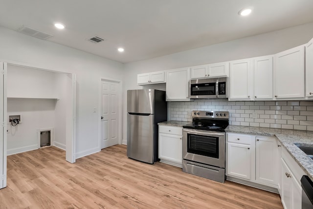 kitchen featuring white cabinets, light stone counters, and stainless steel appliances