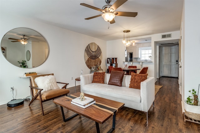 living room with dark wood-type flooring and ceiling fan with notable chandelier