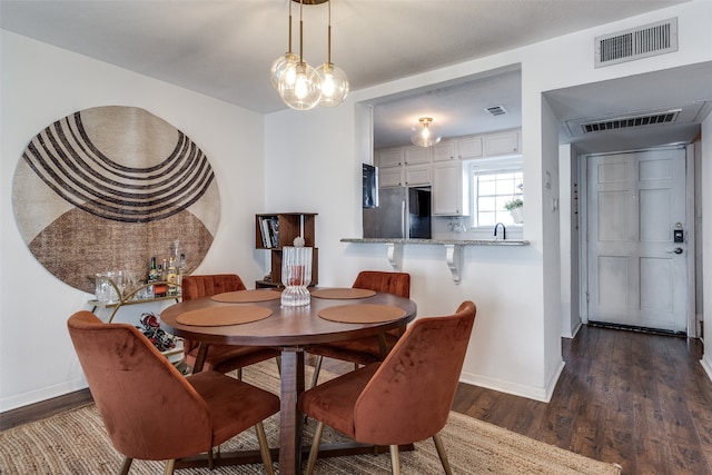 dining space with a chandelier, sink, and dark wood-type flooring