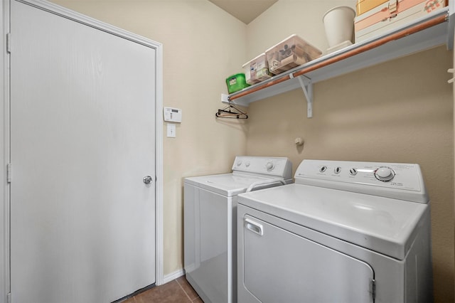 clothes washing area with dark tile patterned floors and washer and clothes dryer