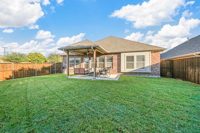 rear view of property with ceiling fan, a yard, and a patio