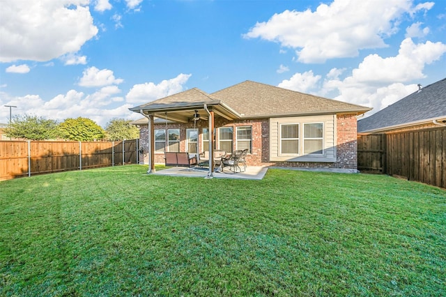 rear view of property featuring ceiling fan, a patio, and a lawn