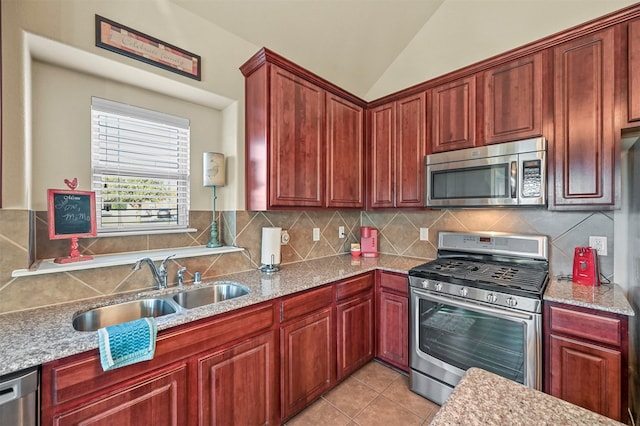 kitchen with decorative backsplash, stainless steel appliances, vaulted ceiling, sink, and light tile patterned floors