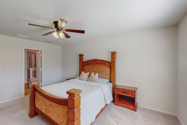 bedroom featuring ensuite bathroom, light colored carpet, and ceiling fan