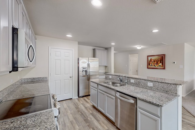 kitchen with sink, light stone counters, stainless steel appliances, and light wood-type flooring