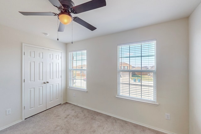 unfurnished bedroom with light carpet, a closet, and ceiling fan