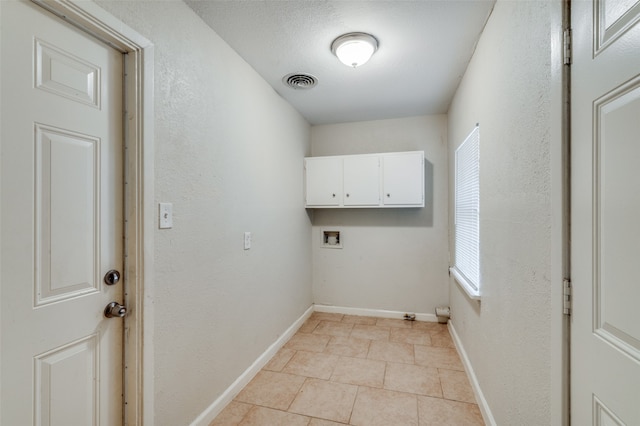 clothes washing area featuring a textured ceiling, washer hookup, and cabinets