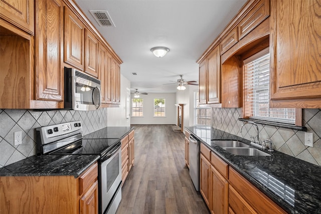 618 W Crawford St, Denison, TX 75020 - kitchen featuring appliances with stainless steel finishes, a sink, backsplash, dark wood-style floors, and dark stone counters