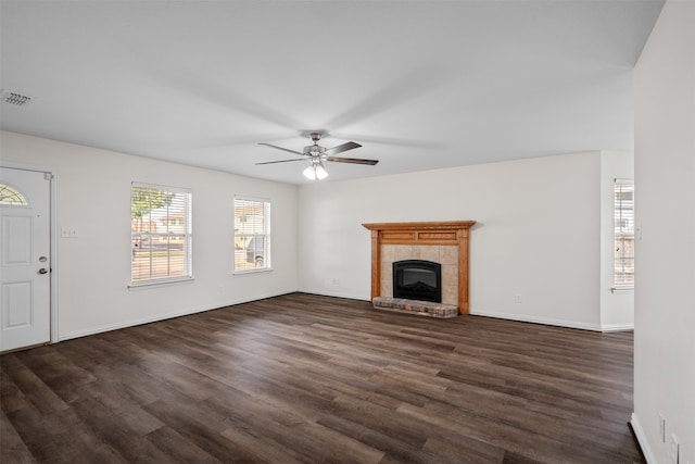 unfurnished living room with ceiling fan, a tiled fireplace, and dark hardwood / wood-style floors