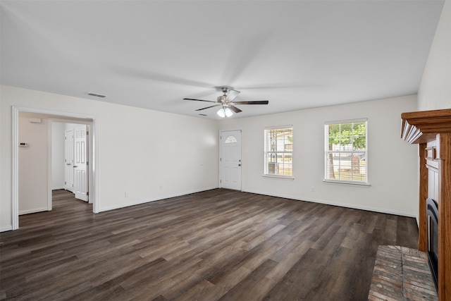 unfurnished living room featuring dark wood-type flooring, ceiling fan, and a brick fireplace