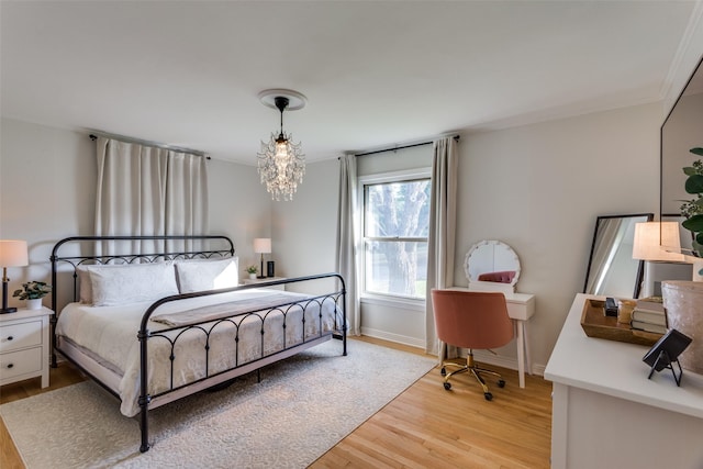 bedroom with light wood-style flooring, baseboards, and a chandelier
