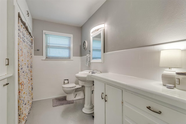 full bath featuring toilet, wainscoting, a shower with curtain, and tile walls