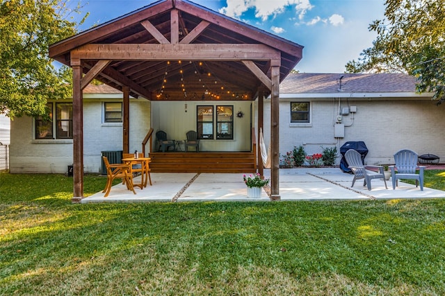back of house featuring brick siding, a patio, a lawn, central AC, and roof with shingles
