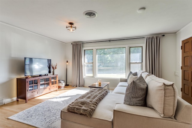 living area featuring light wood-style floors, ornamental molding, and baseboards