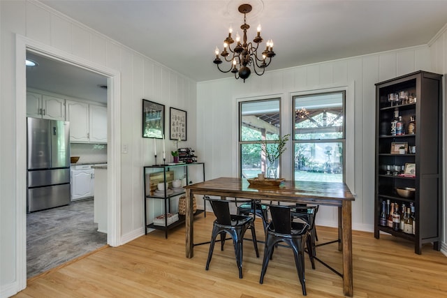 dining room featuring ornamental molding, light wood-style floors, and a chandelier