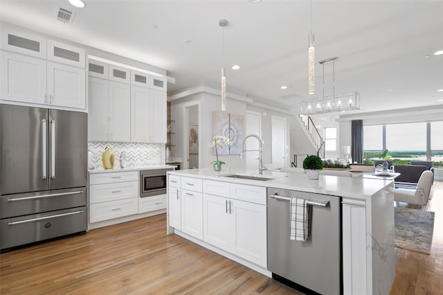 kitchen with white cabinets, stainless steel appliances, sink, and decorative light fixtures