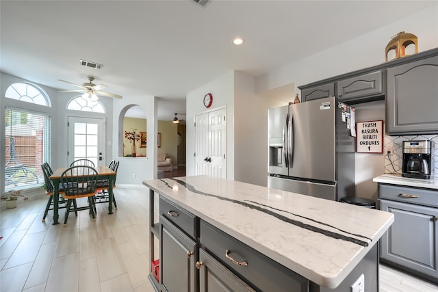 kitchen featuring gray cabinetry, ceiling fan, a kitchen island, and stainless steel refrigerator with ice dispenser