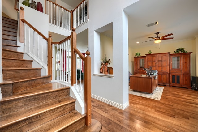 staircase featuring hardwood / wood-style flooring, ceiling fan, and ornamental molding