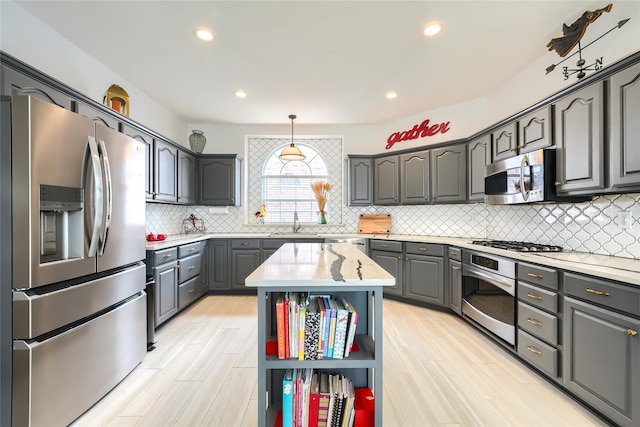 kitchen featuring gray cabinetry, pendant lighting, a center island, sink, and appliances with stainless steel finishes