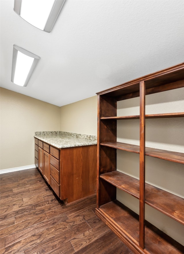 interior space with light stone counters and dark hardwood / wood-style floors