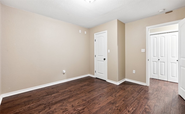 unfurnished bedroom featuring dark wood-type flooring, a textured ceiling, and a closet