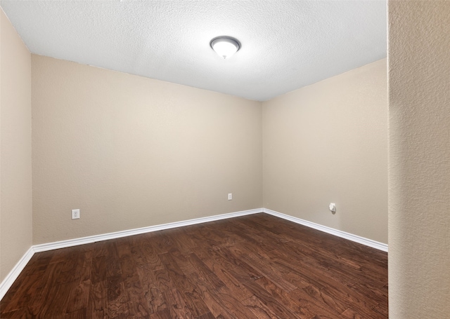 empty room with dark hardwood / wood-style floors and a textured ceiling