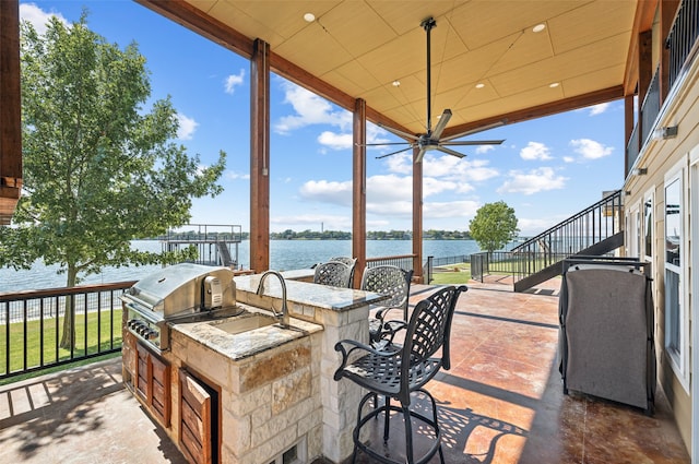 view of patio with grilling area, an outdoor kitchen, an outdoor wet bar, a water view, and ceiling fan