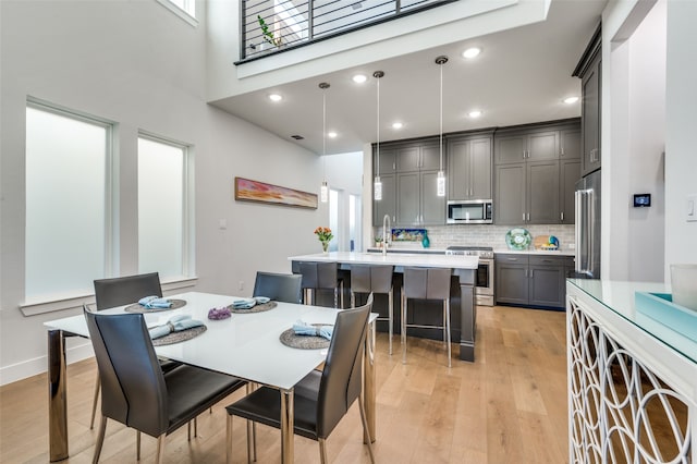 dining space featuring light hardwood / wood-style flooring and a high ceiling