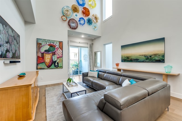 living room featuring a towering ceiling and light hardwood / wood-style flooring