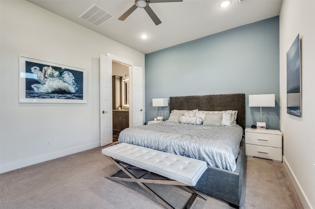 bedroom with connected bathroom, light colored carpet, and ceiling fan