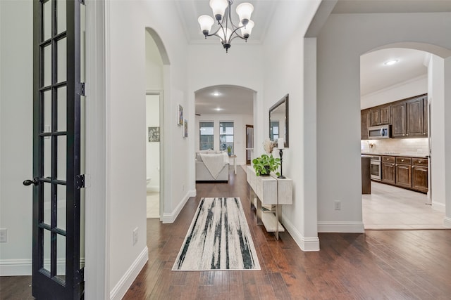 foyer featuring french doors, hardwood / wood-style flooring, an inviting chandelier, and crown molding