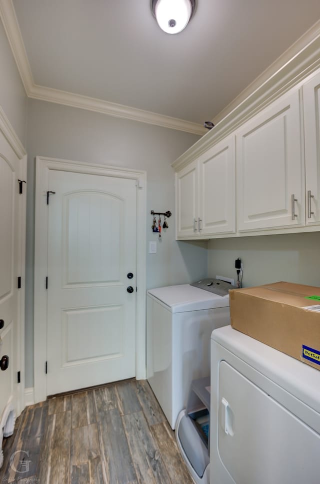 laundry area with hardwood / wood-style flooring, washing machine and dryer, cabinets, and ornamental molding