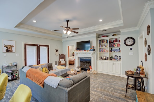 living room with crown molding, a raised ceiling, a fireplace, and dark hardwood / wood-style flooring