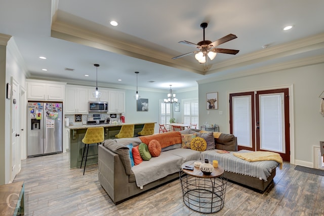 living room with ornamental molding, a tray ceiling, and light hardwood / wood-style floors