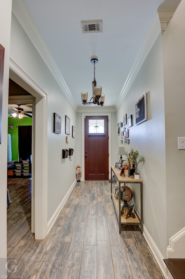 foyer entrance featuring crown molding, hardwood / wood-style flooring, and ceiling fan with notable chandelier