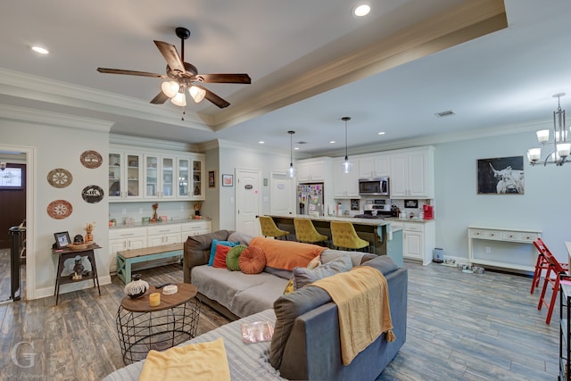 living room featuring crown molding, a tray ceiling, ceiling fan with notable chandelier, and dark hardwood / wood-style flooring