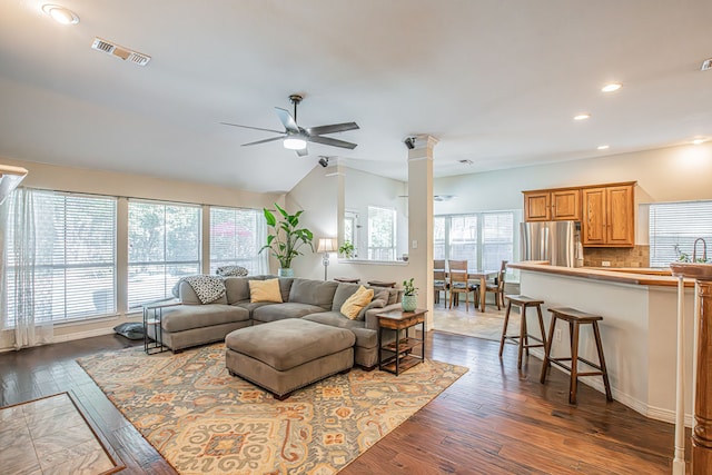 living room with dark wood-type flooring, ceiling fan, and ornate columns