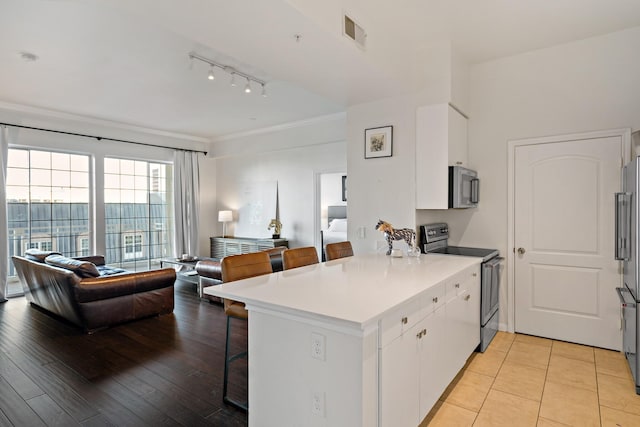 kitchen with white cabinetry, a breakfast bar area, light hardwood / wood-style floors, kitchen peninsula, and stainless steel appliances