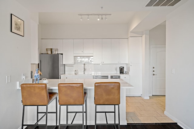 kitchen with a kitchen bar, appliances with stainless steel finishes, white cabinetry, and sink