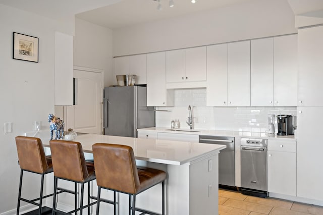 kitchen featuring a kitchen breakfast bar, white cabinetry, sink, and appliances with stainless steel finishes