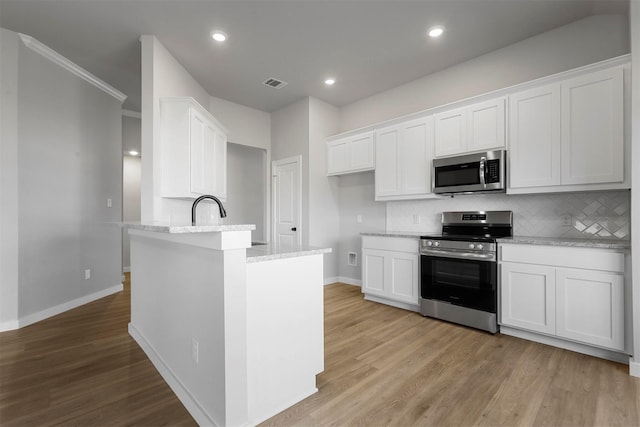 kitchen featuring light wood-type flooring, white cabinetry, stainless steel appliances, and tasteful backsplash