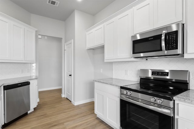 kitchen with white cabinets, stainless steel appliances, and light stone counters