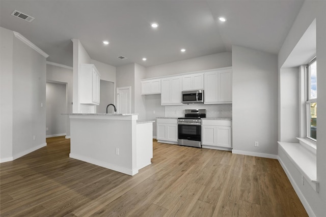 kitchen featuring appliances with stainless steel finishes, backsplash, light hardwood / wood-style floors, and white cabinetry