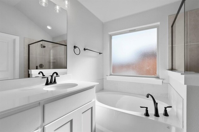 bathroom with vanity, lofted ceiling, and independent shower and bath