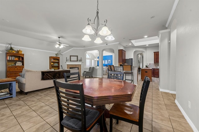 tiled dining area with ceiling fan with notable chandelier, crown molding, and lofted ceiling