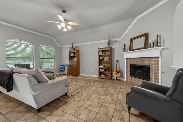 tiled living room with ceiling fan, crown molding, vaulted ceiling, and a tiled fireplace