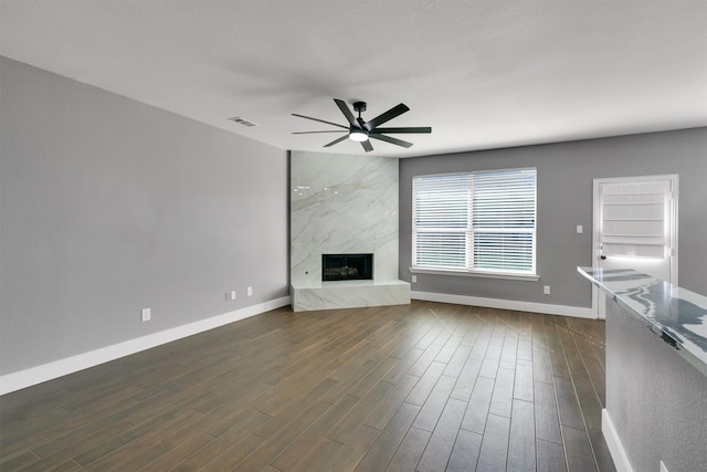 unfurnished living room featuring a high end fireplace, a textured ceiling, dark hardwood / wood-style floors, and ceiling fan