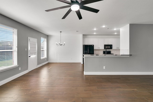 kitchen with kitchen peninsula, white cabinets, dark hardwood / wood-style flooring, black appliances, and pendant lighting