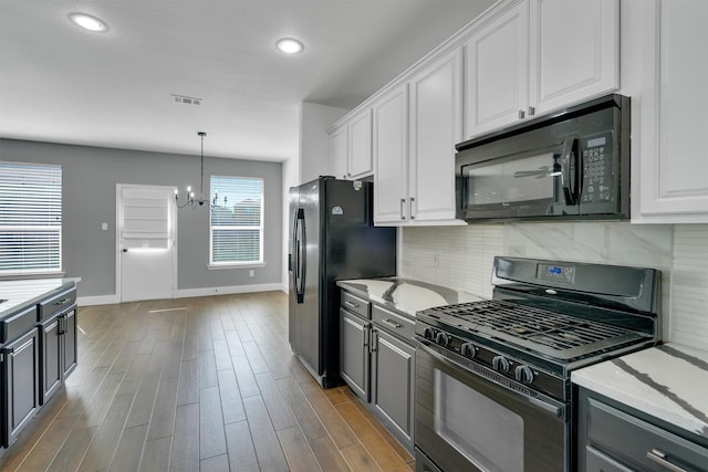 kitchen featuring decorative backsplash, white cabinets, dark hardwood / wood-style floors, black appliances, and a notable chandelier